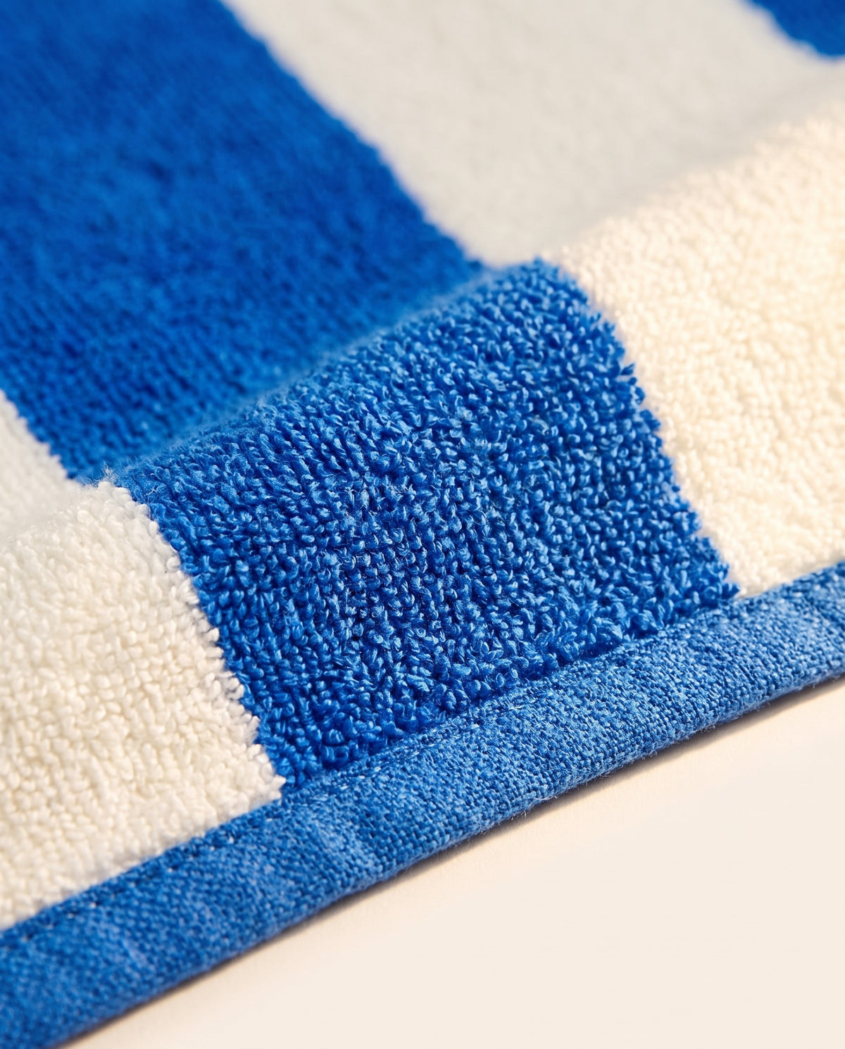 Toalla playera de rayas azul cobalto, detalle de la tela y el logo